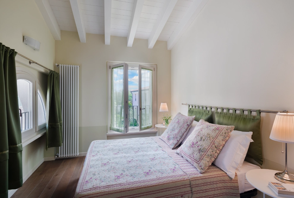 Spacious double bedroom in the one-bedroom apartment at Palazzo Scolari, Polpenazze, featuring a welcoming design and modern finishes.
