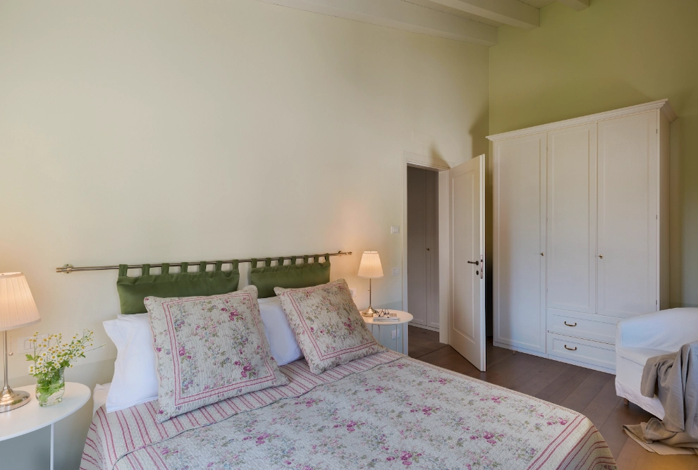 Detail of the double bedroom with green walls in the one-bedroom apartment at Palazzo Scolari, Polpenazze, offering a relaxing and uniquely designed atmosphere.